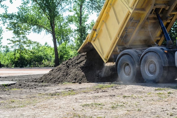 Yellow dump truck unloading dirt