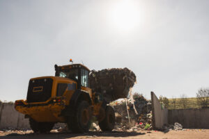 Yellow skid steer lifting debris