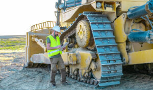 Worker inspecting large construction machinery.ai repair maintenance monitoring