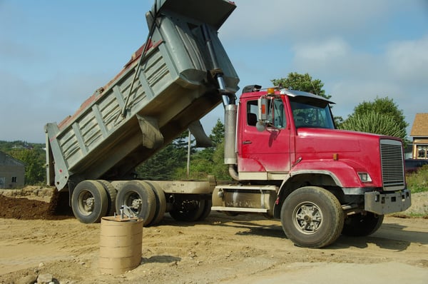 Red dump truck unloading dirt